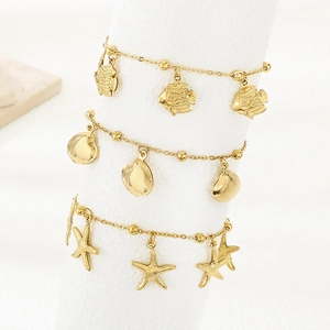 Macro detail of gold plated charms featuring tropical fish, seashell, and starfish designs