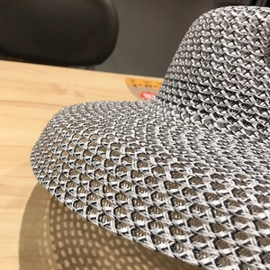 Gros plan sur la texture tissée ajourée noir et blanc de ce chapeau de soleil en paille