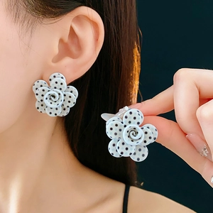 Détail de boucles d'oreilles fleurs bleu clair à pois noirs avec tige en argent pur