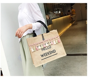 Detail of jute tote bag with colorful tassels and Hello Weekend print in natural linen
