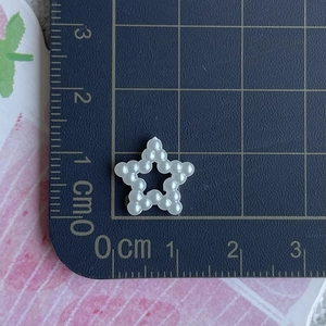 Macro view of a white pearlized star charm for DIY hair accessories on a cutting mat