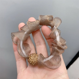 Close-up of brown mesh scrunchie featuring elegant gold rhinestone ball detail