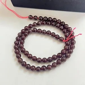 Vue détaillée de perles de grenat naturel rouge vin enfilées sur un cordon rouge DIY