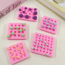 Pink silicone snowflake molds for baking with star and flower shapes on a beige surface