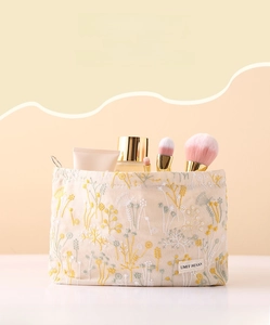 Close-up of floral embroidery on linen makeup bag with various skincare products inside