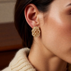 Close-up of vintage gold hollowed-out earrings with lace carving and small white gems