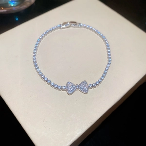 Macro detail of silver bowknot bracelet with shiny zircon inlay on beige jewelry box