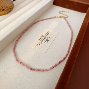 Détail du collier de perles dégradé rose sur plateau avec fermoir mousqueton doré