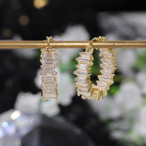 Detailed view of luxury gold hoop earrings with baguette-cut AAA zircons on display