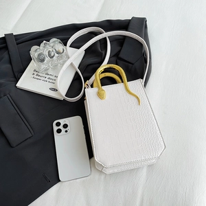 White faux crocodile tote bag featuring unique gold snake-shaped metal handle at 45-degree angle
