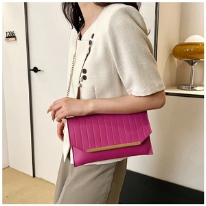 Detail of pink envelope clutch bag with metal chain strap and elegant gold trim