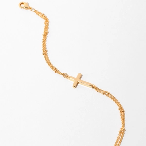 Detail of three-layer gold beaded chain bracelet featuring a polished cross charm