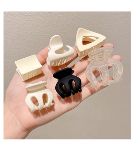 Detailed close-up of matte geometric hair claws in beige, black, and clear finishes