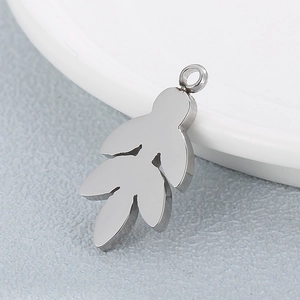 Polished silver leaf pendant made of stainless steel displayed on a ceramic dish edge