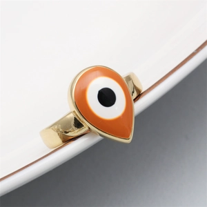 Macro shot of orange Evil Eye open ring in drop shape with gold plating and pavé details