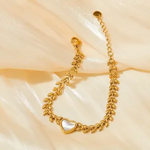 Golden wheat link bracelet featuring a heart-shaped shell charm on silk background