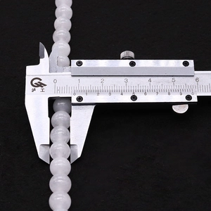 Macro shot of 10mm white jade beads on a digital caliper showing precise round diameter