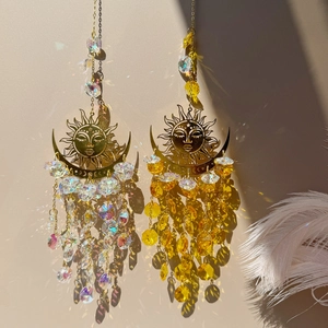 Golden sun and moon crystal suncatchers casting rainbow light reflections on beige wall