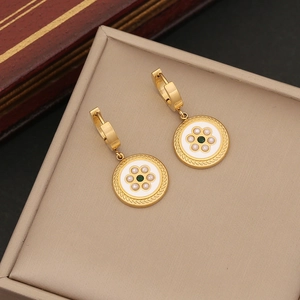 Close-up of gold hoop earrings with white enamel charms and green stone centers