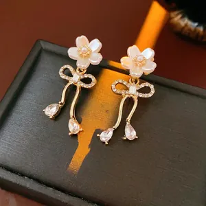Boucles d'oreilles nœud dorées avec fleurs en nacre et pendentifs en cristal