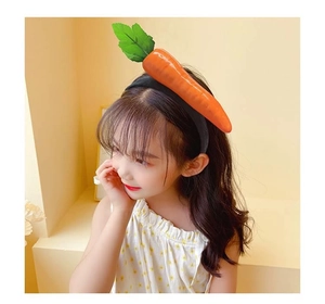 Detail of child wearing a black headband with a large realistic orange carrot decor