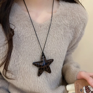 Close-up of model wearing a leopard print star pendant necklace with black cord
