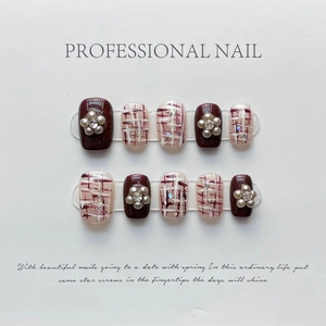 Detalle de uñas postizas hechas a mano en color burdeos con flores de perlas y tweed