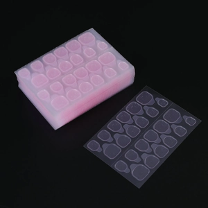Detailed view of clear double-sided adhesive nail glue tabs in various sizes for manicure