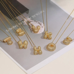 Bubble initial pendant necklace with gold plating and cubic zirconia on fashion magazine