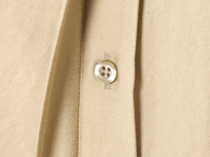 Macro shot of sewing details and pearl button on beige twill wide-leg trousers