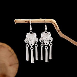 Detail of leaf-inspired silver ethnic tassel earrings hanging on natural wood