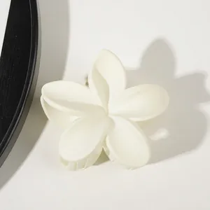Macro view of matte white plumeria flower hair claw clip with elegant petal details
