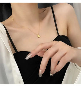 Detailed close-up of a gold heart pendant necklace worn on a woman's neck