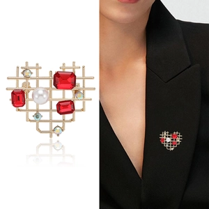 Hollow gold heart brooch with red gemstones and pearl shown on white and model wear
