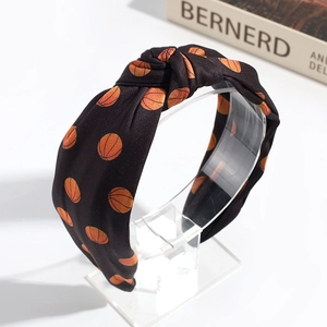 Detailed view of black fabric knotted headband with orange basketball print on display