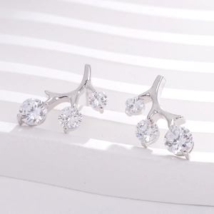 Macro detail of silver branch-shaped stud earrings with three sparkling white zircons