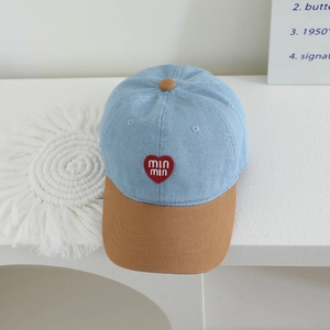Close-up of color-blocked denim baseball cap featuring heart embroidery and stitching details