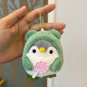 Close-up of a plush penguin keychain wearing a green hoodie and holding a lollipop