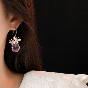 Gros plan d'un crochet d'oreille papillon avec cristal goutte violet sur un modèle