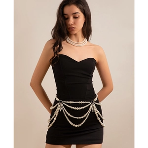 Detailed view of multilayered pearl body chain and necklace on a black outfit