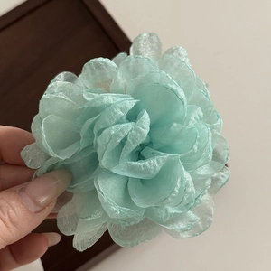 Detail shot of light blue organza rose hair claw showing soft texture and petal layers