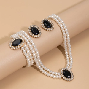 Close-up of vintage jewelry set with black faux gems, rhinestones and layered pearls
