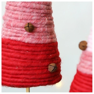 Detailed view of pink gradient wool yarn Christmas tree with vintage metal bell accents