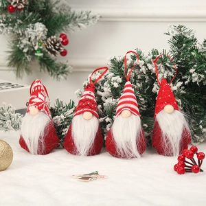 Set of four red and white knitted Christmas gnome ornaments with plush beards on artificial snow