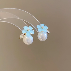 Macro shot of blue flower earrings with rhinestone details and large white pearls