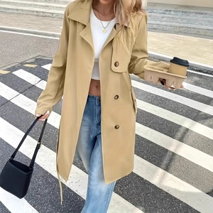Outdoor street shot of a khaki long trench coat with classic lapels and double-breasted detail