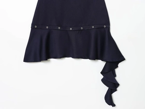 Close-up of asymmetrical hem on navy blue dress with metal rivets and ruffle detail