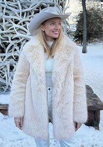 Détail d'un manteau en fausse fourrure crème avec grand col à revers dans un décor de neige