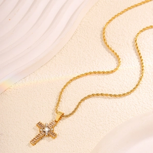 Macro shot of gold cross pendant necklace with zircon inlay and twisted rope chain