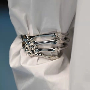 Macro shot of silver metal skeleton hand cuff bracelet worn over a white shirt sleeve